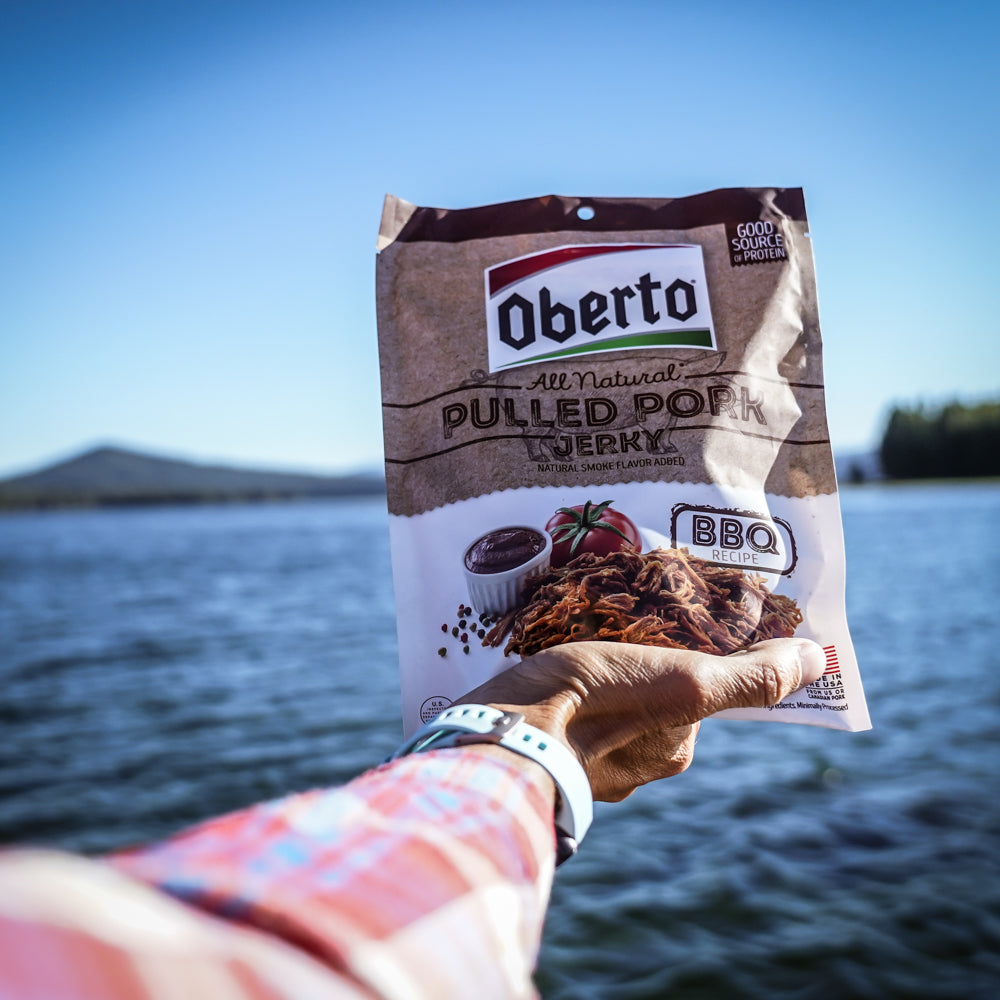 Arm stretched out holding Oberto Pulled Pork jerky on a PNW lake 