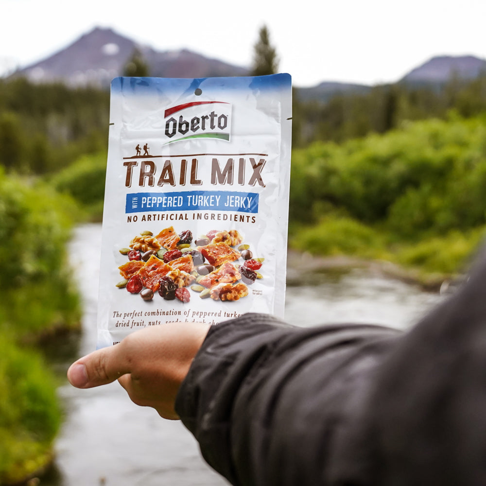 Hand holding bag of Turkey Trail Mix near a PNW stream