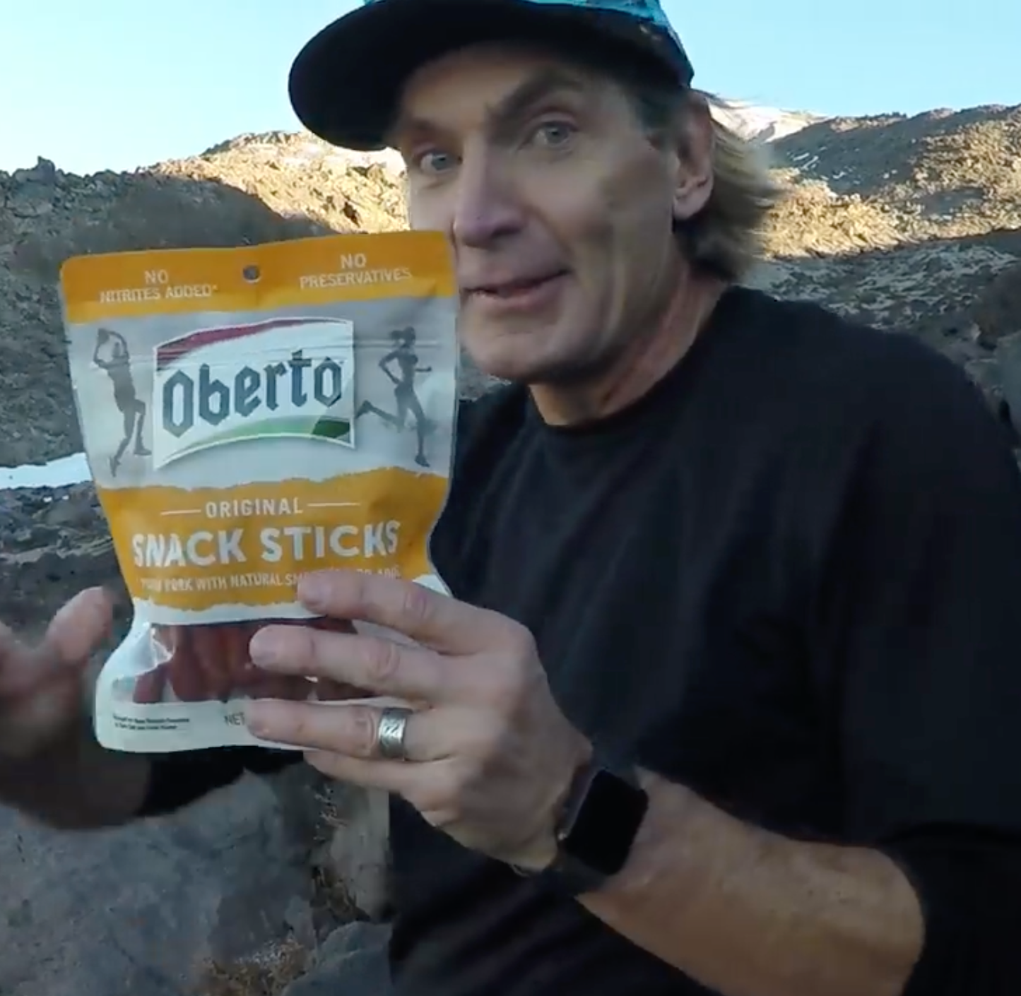 CEO, Tom Hernquist poses for a picture on top of Mount St. Helens with a bag of Oberto Meat Sticks
