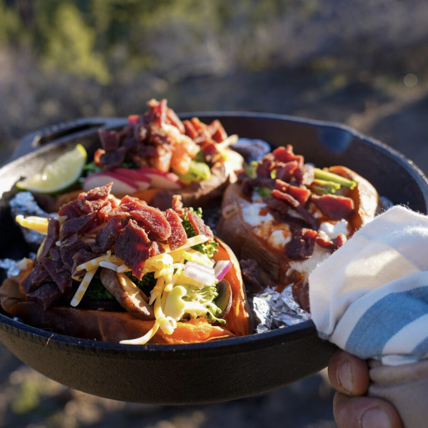 Skillet full of campfire potatoes topped with jerky.