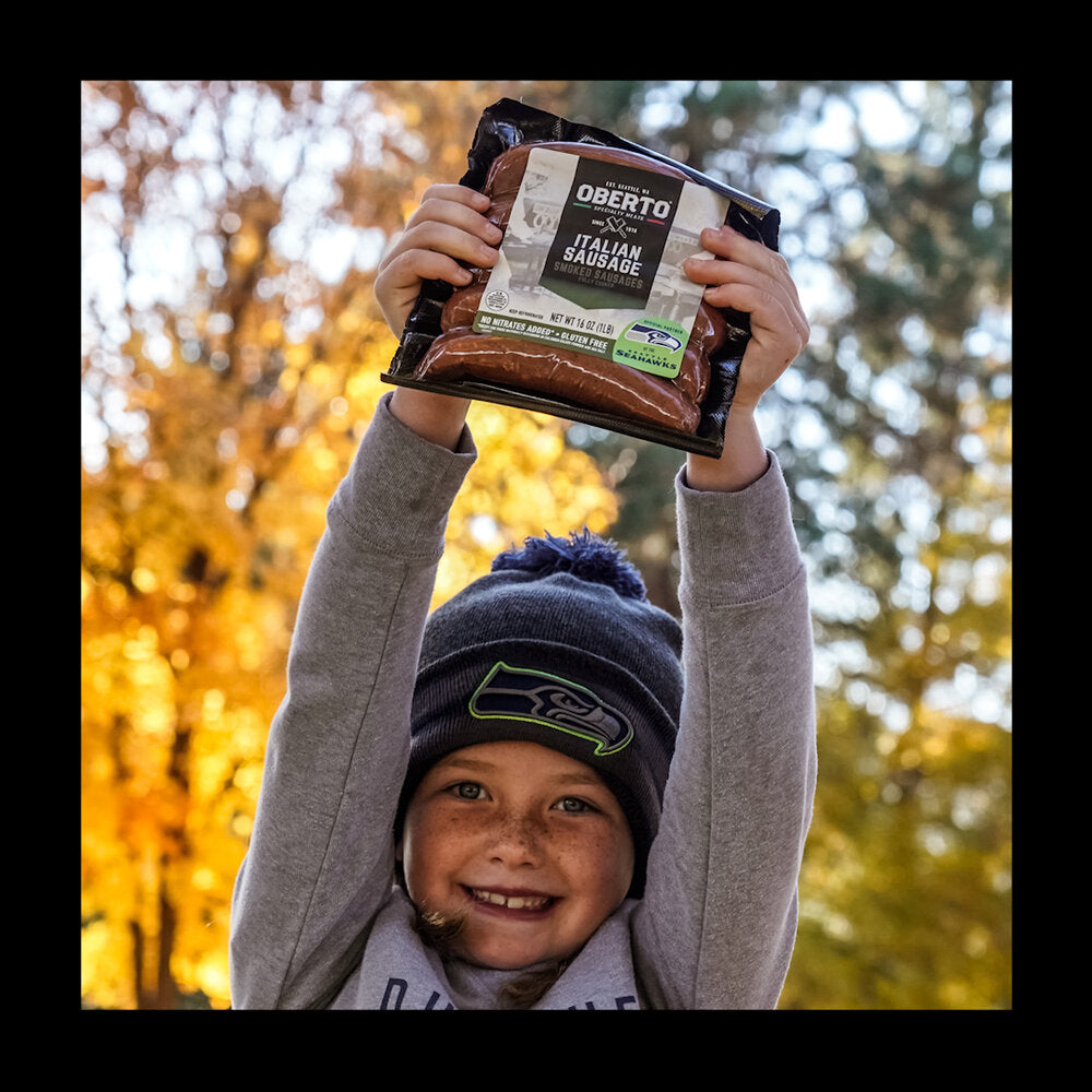 Young girl holds a pack of Oberto Sausages over her head in excitement on a fall day