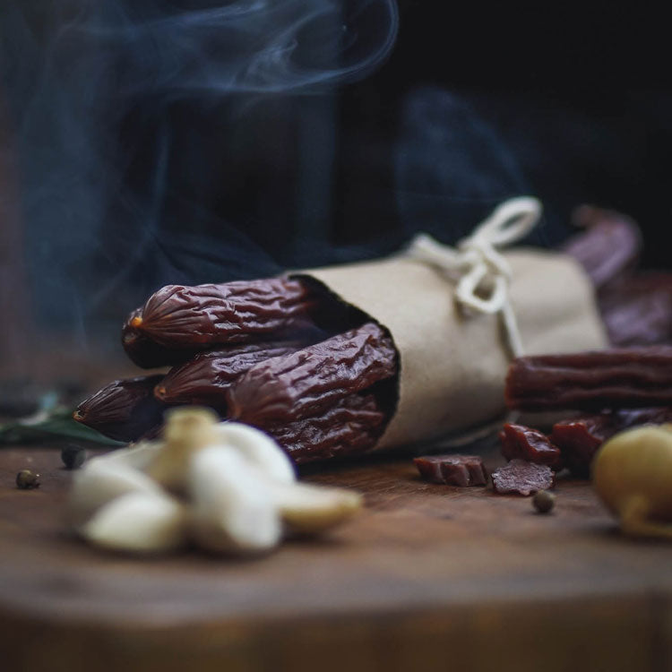 Oberto Classic Smoked Sausages resting on a cutting board and surrounded by raw ingredients 